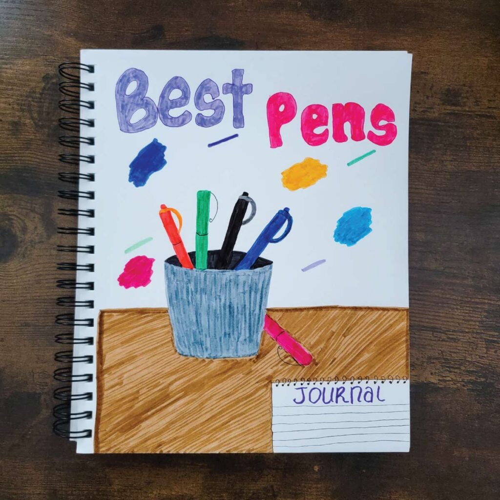 Best pens. Hand drawn page of a cup of pens on a table with a journal in front of it.